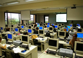 多数のパソコンが並ぶ教室で生徒が勉強している様子の画像